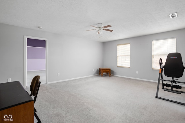 carpeted home office featuring a textured ceiling and ceiling fan