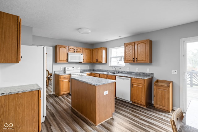 kitchen featuring sink, dark hardwood / wood-style floors, a textured ceiling, white appliances, and a kitchen island