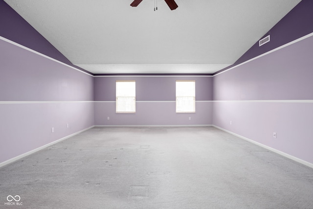 spare room featuring light carpet, ceiling fan, and vaulted ceiling