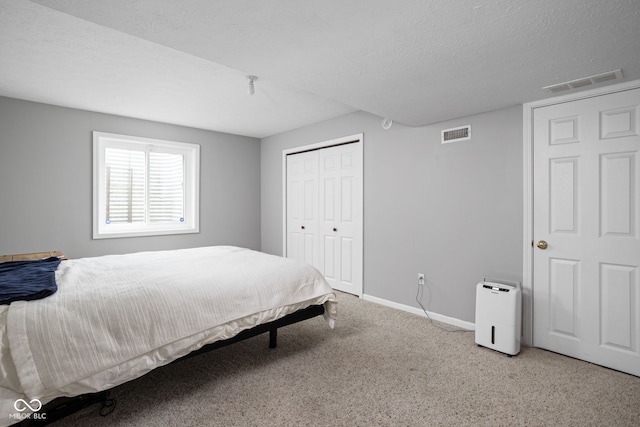 bedroom featuring a closet, light colored carpet, and a textured ceiling