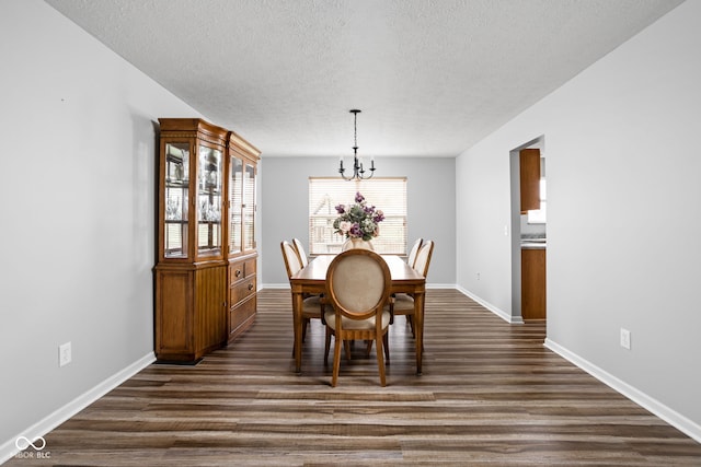 dining space with a textured ceiling, dark wood-type flooring, and a notable chandelier