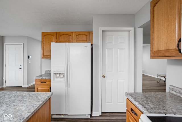 kitchen with a textured ceiling, white appliances, and dark wood-type flooring