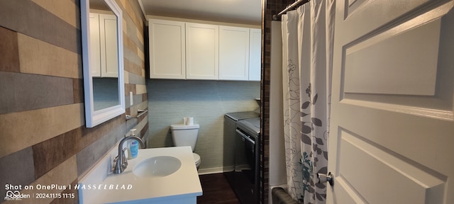 bathroom featuring washing machine and clothes dryer, sink, and toilet