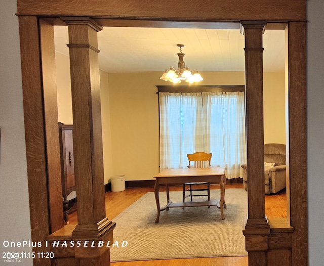 office area featuring ornate columns, a notable chandelier, and light wood-type flooring