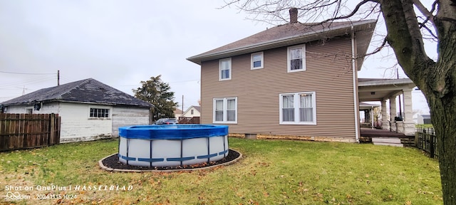 back of property with a yard and a covered pool