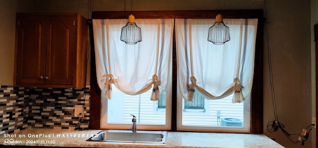 room details featuring decorative light fixtures, tasteful backsplash, and sink