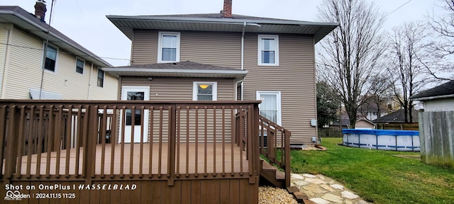 back of house featuring a swimming pool side deck and a lawn