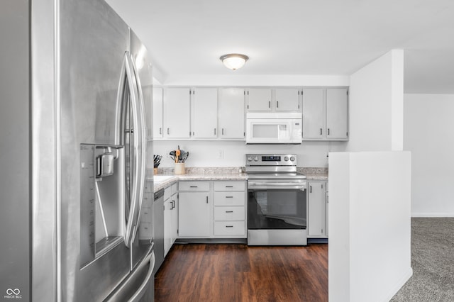 kitchen with appliances with stainless steel finishes, white cabinetry, and dark wood-type flooring