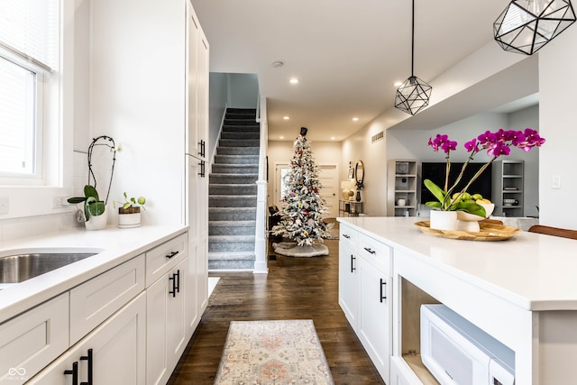 kitchen with white cabinets, hanging light fixtures, and dark wood-type flooring