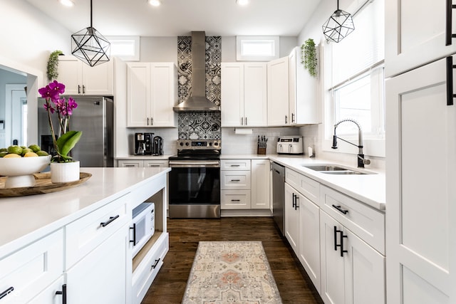 kitchen with plenty of natural light, wall chimney exhaust hood, hanging light fixtures, and appliances with stainless steel finishes