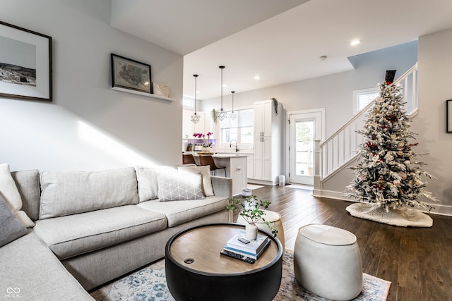 living room featuring sink, dark wood-type flooring, and a notable chandelier