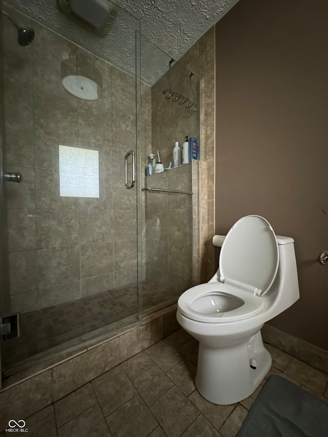 bathroom featuring tile patterned flooring, a shower with door, a textured ceiling, and toilet