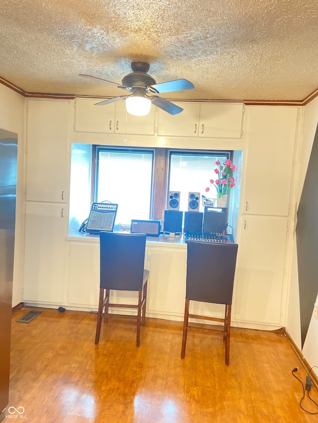 interior space with white cabinets, ceiling fan, light wood-type flooring, and a textured ceiling