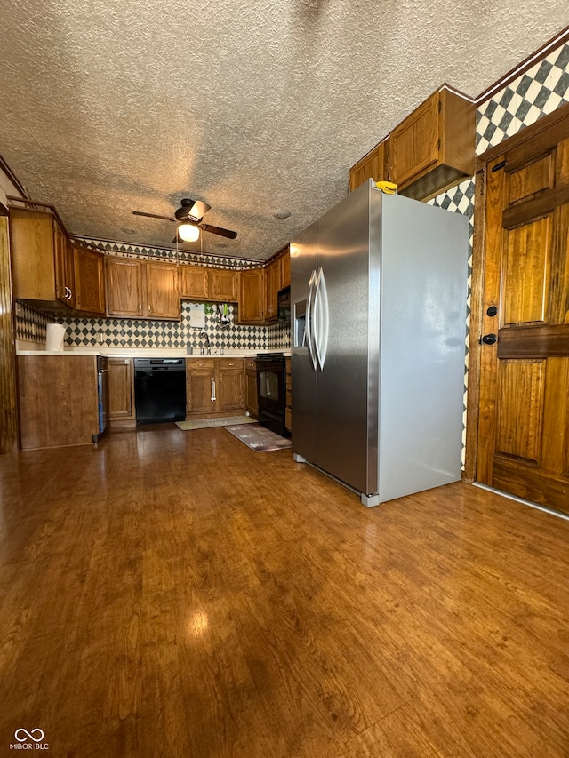 kitchen with black appliances, dark hardwood / wood-style flooring, backsplash, and a textured ceiling