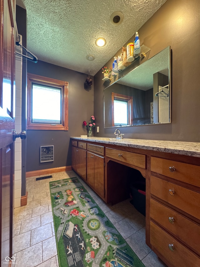 bathroom with heating unit, vanity, and a textured ceiling