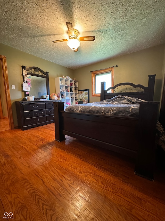 bedroom featuring hardwood / wood-style flooring, ceiling fan, and a textured ceiling