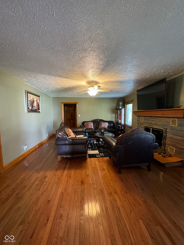 living room featuring hardwood / wood-style flooring, a fireplace, ceiling fan, and a textured ceiling