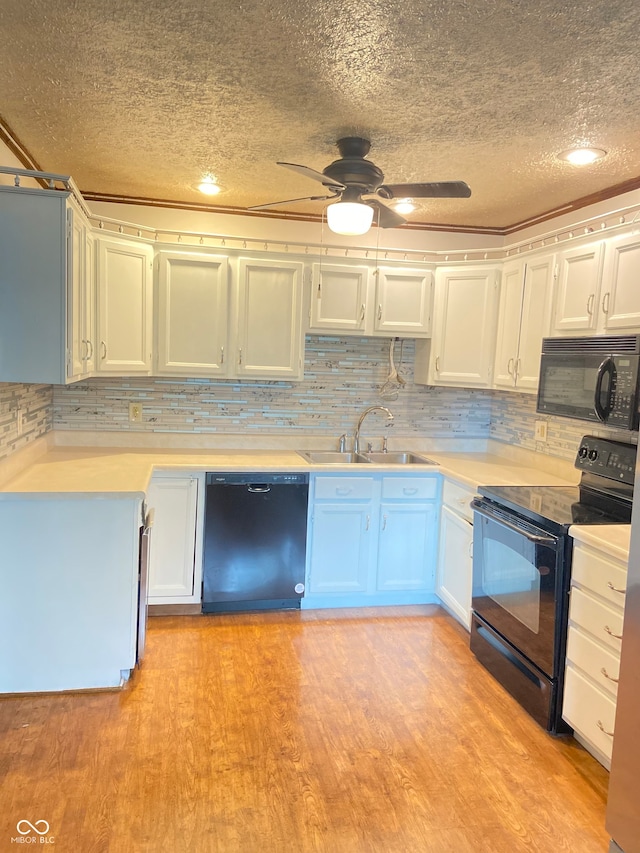 kitchen with sink, light hardwood / wood-style floors, a textured ceiling, white cabinets, and black appliances