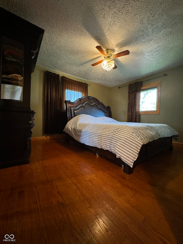 bedroom with hardwood / wood-style floors, a textured ceiling, and ceiling fan