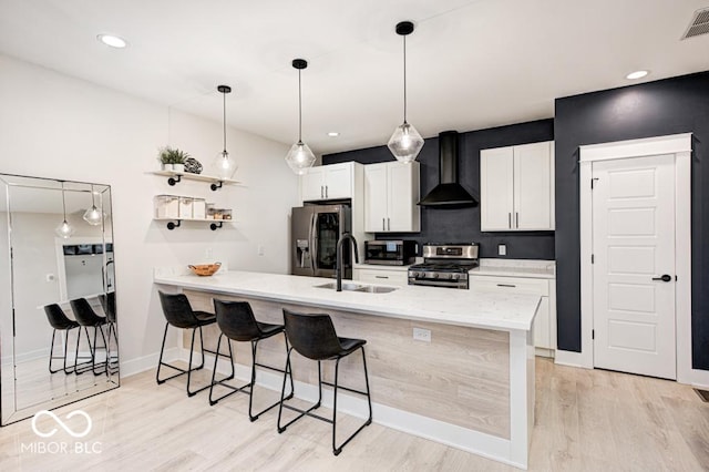 kitchen featuring a breakfast bar area, kitchen peninsula, wall chimney exhaust hood, and appliances with stainless steel finishes