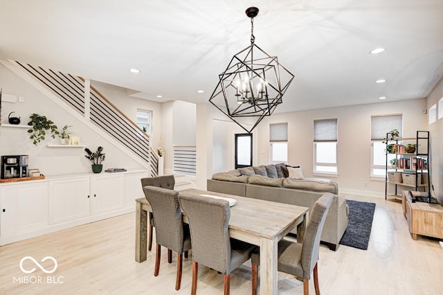 dining space with light hardwood / wood-style flooring and an inviting chandelier