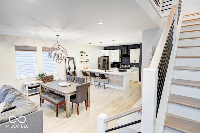 dining space with a chandelier, sink, and light hardwood / wood-style floors