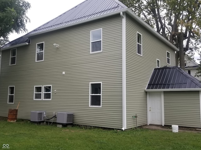 back of property with a yard and central AC unit