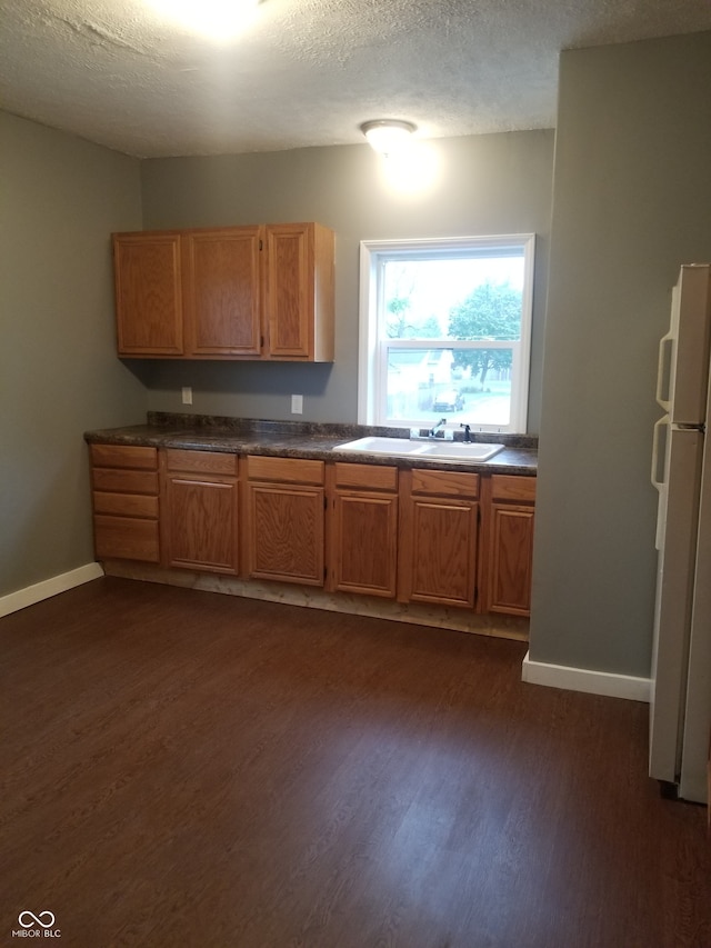 kitchen with a textured ceiling, dark hardwood / wood-style flooring, white refrigerator, and sink