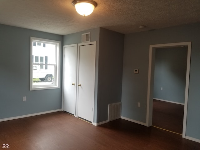 unfurnished bedroom with a textured ceiling, dark hardwood / wood-style flooring, and a closet