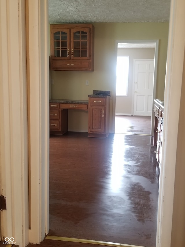 corridor with dark hardwood / wood-style flooring and a textured ceiling