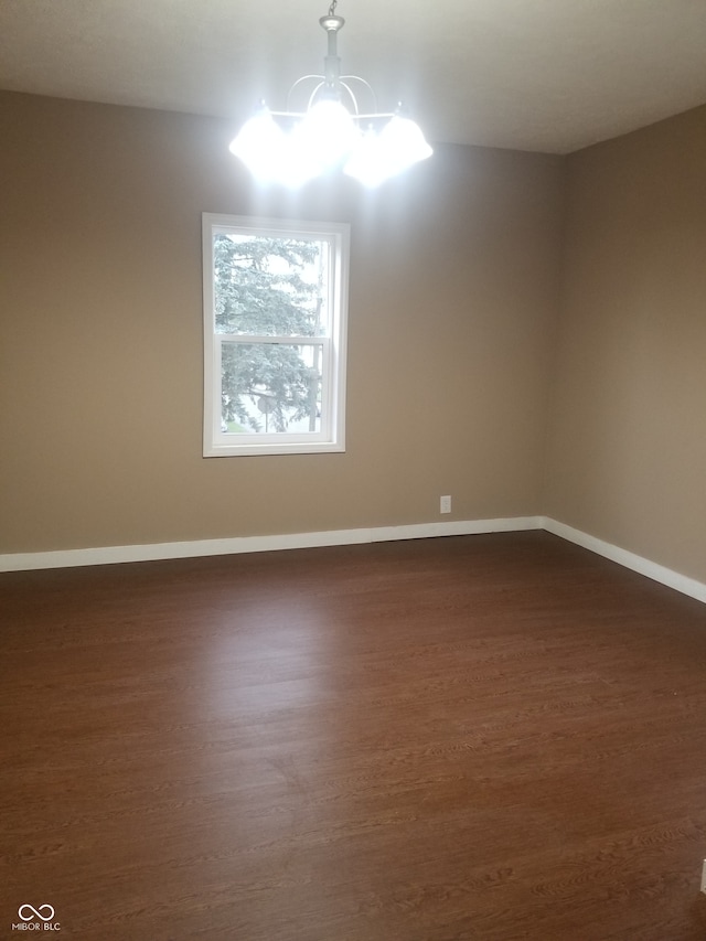 unfurnished room featuring a chandelier and dark hardwood / wood-style flooring