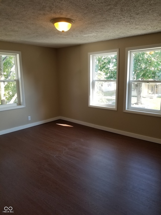 unfurnished room with dark hardwood / wood-style flooring, a healthy amount of sunlight, and a textured ceiling