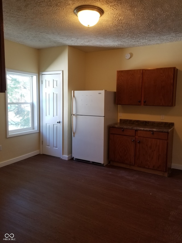 kitchen with white fridge, dark wood-type flooring, and a textured ceiling