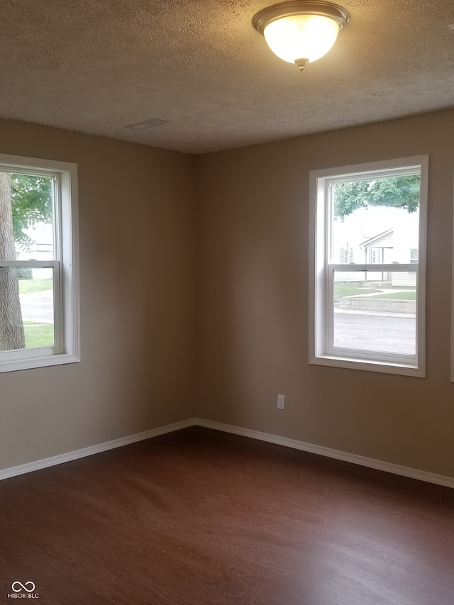 empty room with dark wood-type flooring and a textured ceiling