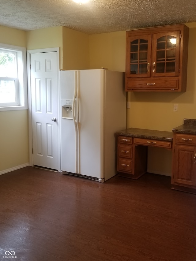 kitchen featuring dark hardwood / wood-style flooring, white fridge with ice dispenser, and a textured ceiling