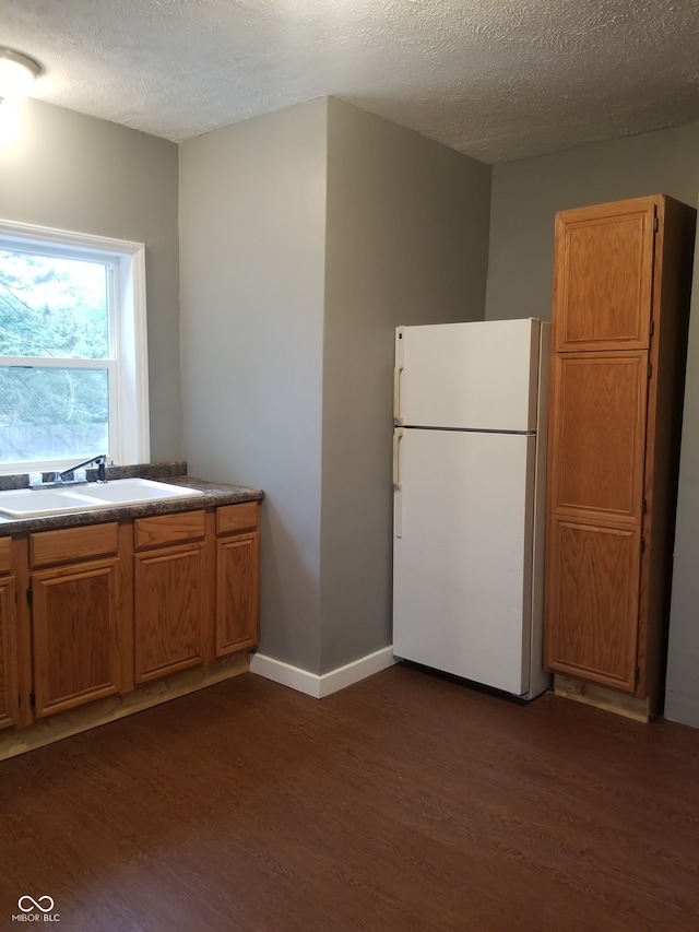 kitchen featuring a textured ceiling, sink, white fridge, and dark hardwood / wood-style floors