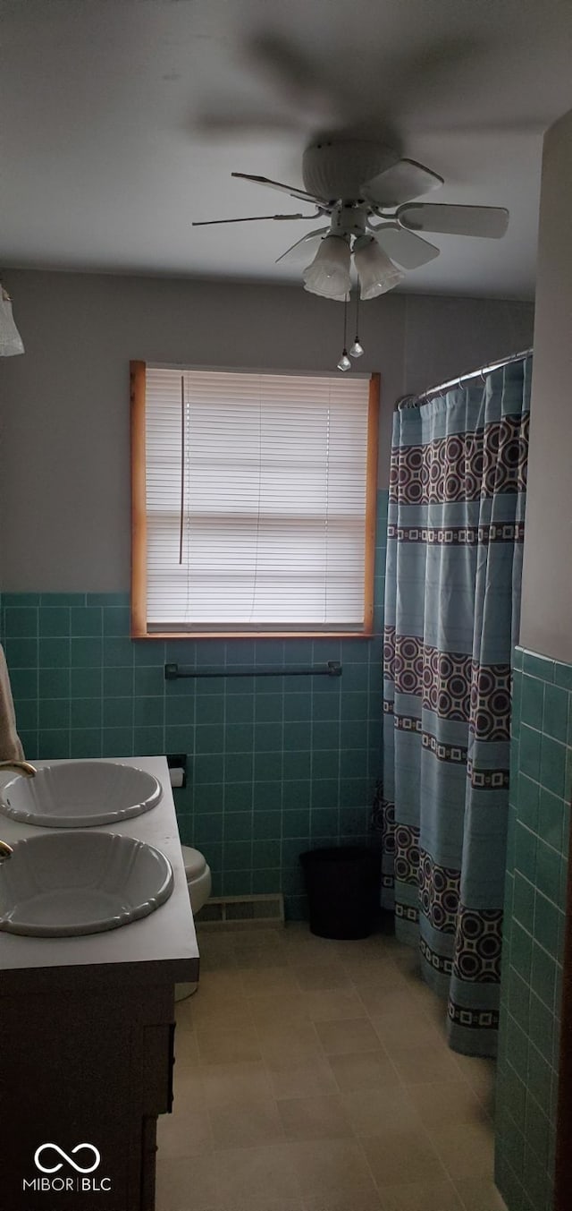 bathroom featuring vanity, ceiling fan, tile walls, toilet, and curtained shower