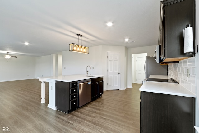 kitchen with hardwood / wood-style floors, sink, hanging light fixtures, an island with sink, and appliances with stainless steel finishes