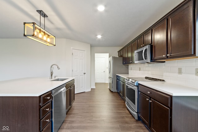 kitchen featuring sink, stainless steel appliances, dark wood-type flooring, tasteful backsplash, and pendant lighting