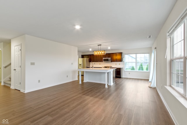 unfurnished living room with a notable chandelier, dark hardwood / wood-style floors, and sink