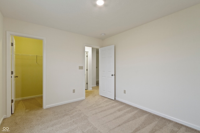 unfurnished bedroom with light carpet, a spacious closet, and a closet