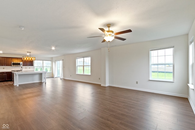 unfurnished living room with ceiling fan, dark wood-type flooring, and a textured ceiling