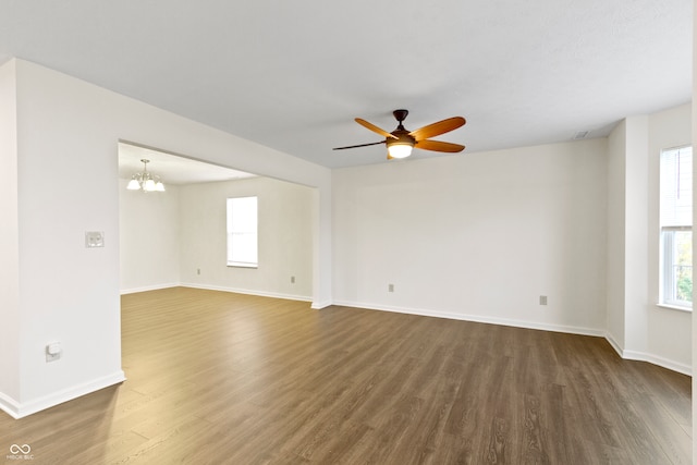 unfurnished room featuring ceiling fan with notable chandelier, dark hardwood / wood-style flooring, and a healthy amount of sunlight