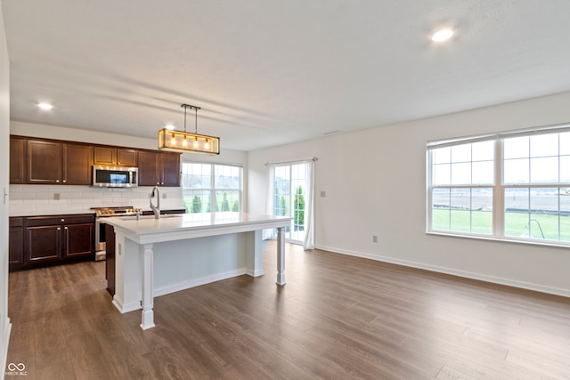 kitchen with pendant lighting, stainless steel appliances, and dark wood-type flooring