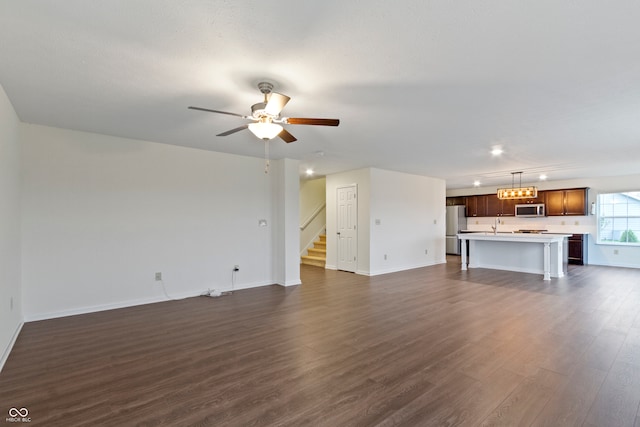 unfurnished living room featuring ceiling fan, sink, and dark wood-type flooring