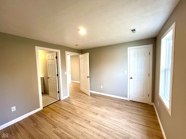 unfurnished bedroom featuring a textured ceiling and light hardwood / wood-style flooring