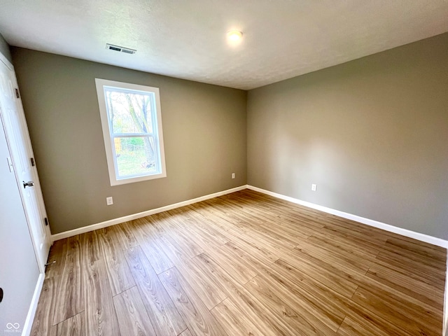 unfurnished room with a textured ceiling and light hardwood / wood-style flooring