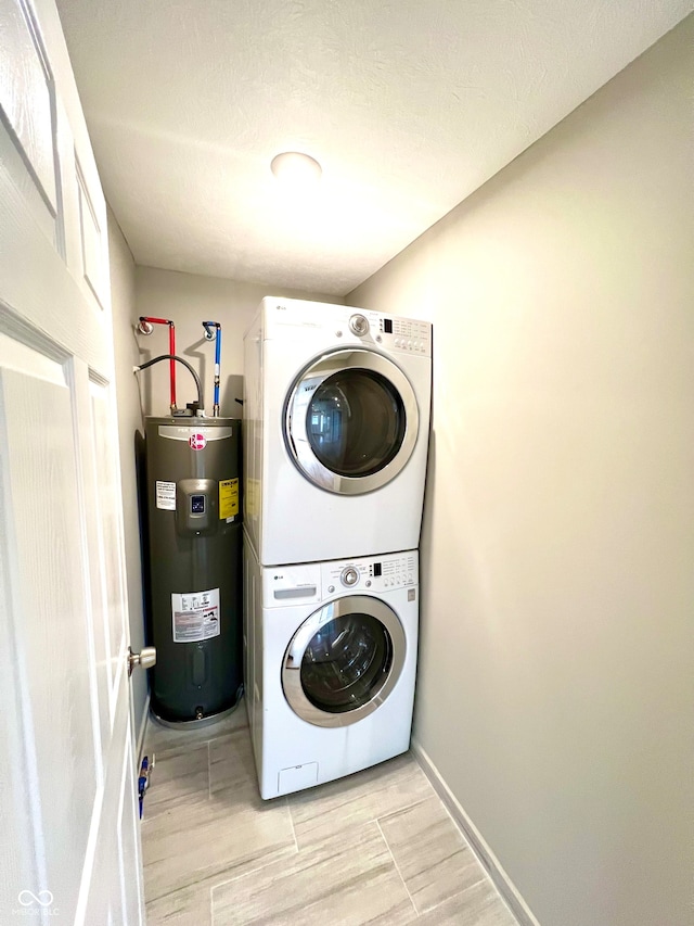 laundry room featuring electric water heater, light hardwood / wood-style floors, and stacked washer / drying machine