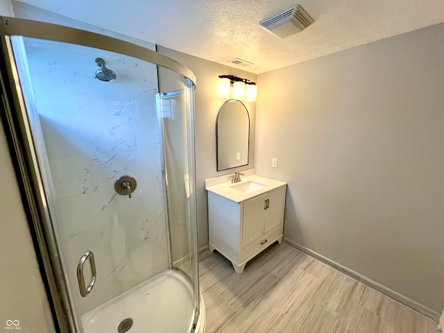 bathroom featuring vanity, wood-type flooring, a textured ceiling, and walk in shower