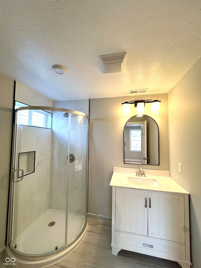 bathroom featuring walk in shower, vanity, a textured ceiling, and hardwood / wood-style flooring